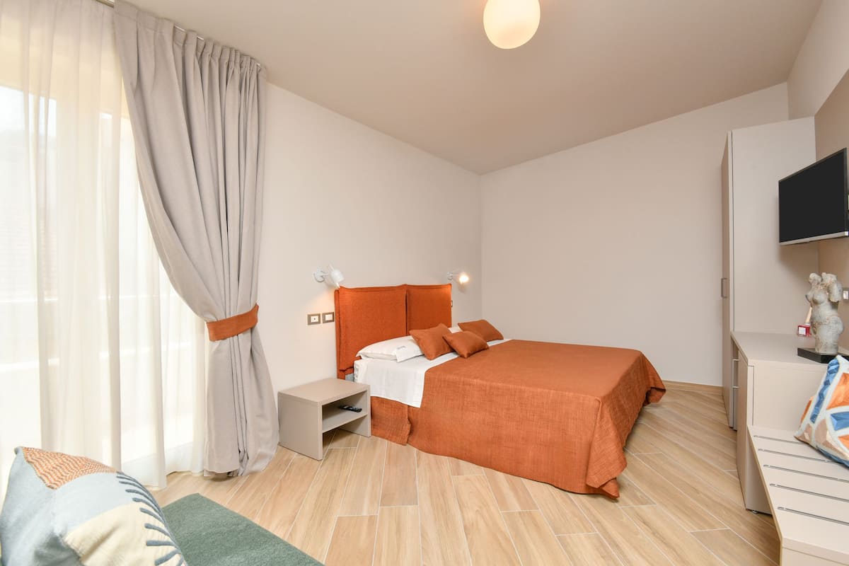 Ein modernes Schlafzimmer mit Bett, Nachttisch und Fernseher.