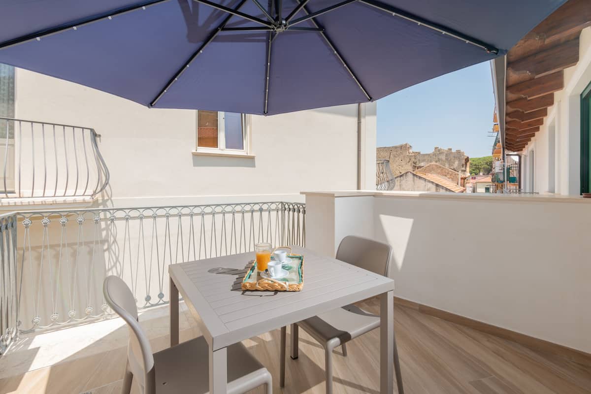 Ein Balkon mit Tisch, Stühlen und Sonnenschirm.
