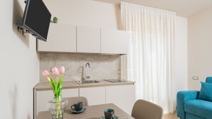 A modern kitchen with a marble backsplash, a built-in sink, and a dining area with a table and chairs. - Odissea Residence e Rooms (Castellabate)