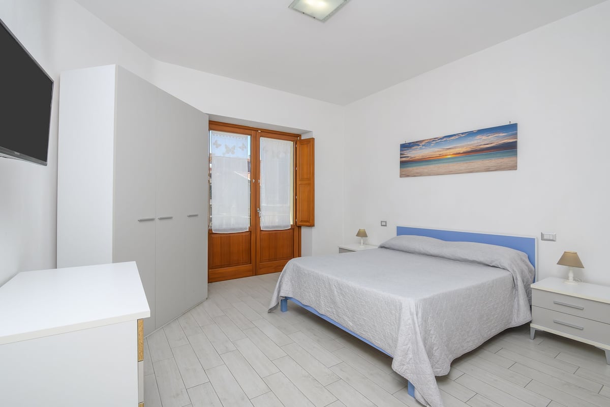 Ein Schlafzimmer mit einem Bett, Nachttischen, einem Kleiderschrank und einem Bild an der Wand.