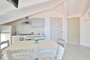 A modern kitchen with a dining table, chairs, and a blue vase.