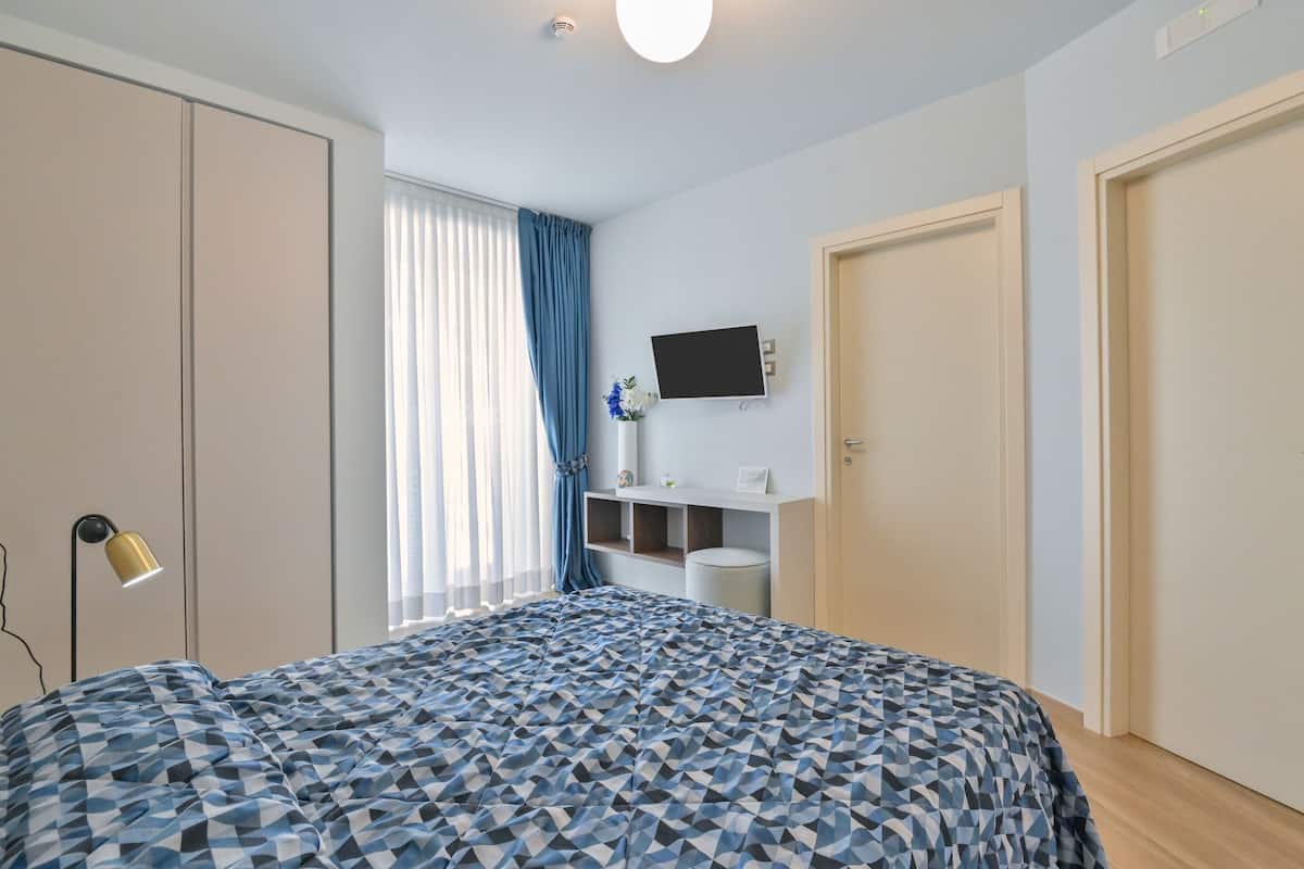 Ein Schlafzimmer mit einem Bett, einem Fernseher, einem Schreibtisch und einem Kleiderschrank.