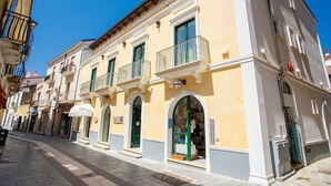 A row of yellow buildings with balconies and storefronts, including a visible sign for 'AQUA BRAVO'. - Odissea Residence e Rooms (Castellabate)