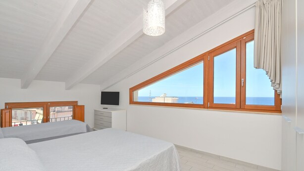 A bedroom with a large window, a bed, a dresser, and a television. - Odissea Residence e Rooms (Castellabate)