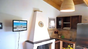 A kitchen with a built-in stove, a refrigerator, and a dining area with a table and chairs. - Casa Anselmi (Portoferraio)