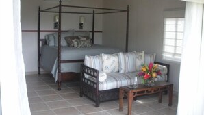 A bedroom with a four-poster bed, a sofa, and a coffee table. - Quaint Studio Cottage with private pool overlooking beautiful Coral Bay (Coral Bay)