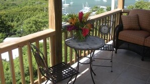 A balcony with a table and chairs, overlooking a marina with boats. - Quaint Studio Cottage with private pool overlooking beautiful Coral Bay (Coral Bay)