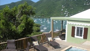 A deck with outdoor seating and a pool, overlooking a marina with boats. - Quaint Studio Cottage with private pool overlooking beautiful Coral Bay (Coral Bay)