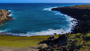 A coastal landscape with a rocky cliff and a beach. - NEW! PonoMana Oasis - The Koi Cottage (Captain Cook)