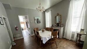 Un comedor con una mesa y sillas de madera, una araña y una chimenea con un espejo.
