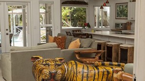 Un salon avec une grande statue de tigre, un canapé gris et une table basse en bois.