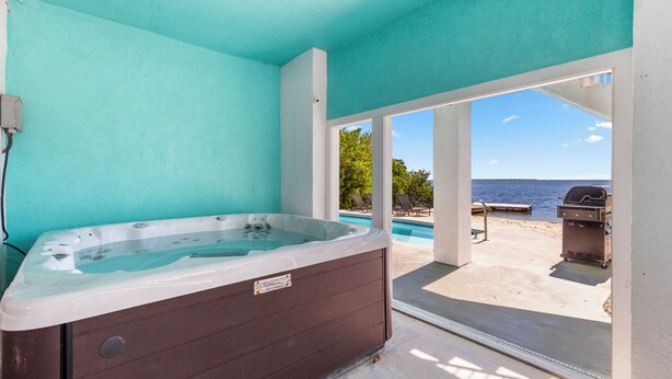 A spa area with a hot tub, a view of the beach, and outdoor seating. - Family Retreat Ocean front pool (Cudjoe Key)