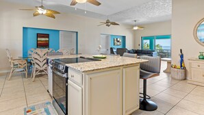 A spacious kitchen with a central island, two ceiling fans, and a dining area with wicker chairs. - Family Retreat Ocean front pool (Cudjoe Key)