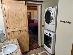 Ein kleiner Hauswirtschaftsraum mit Waschmaschine, Trockner und einer Holztür, die in ein Schlafzimmer führt.