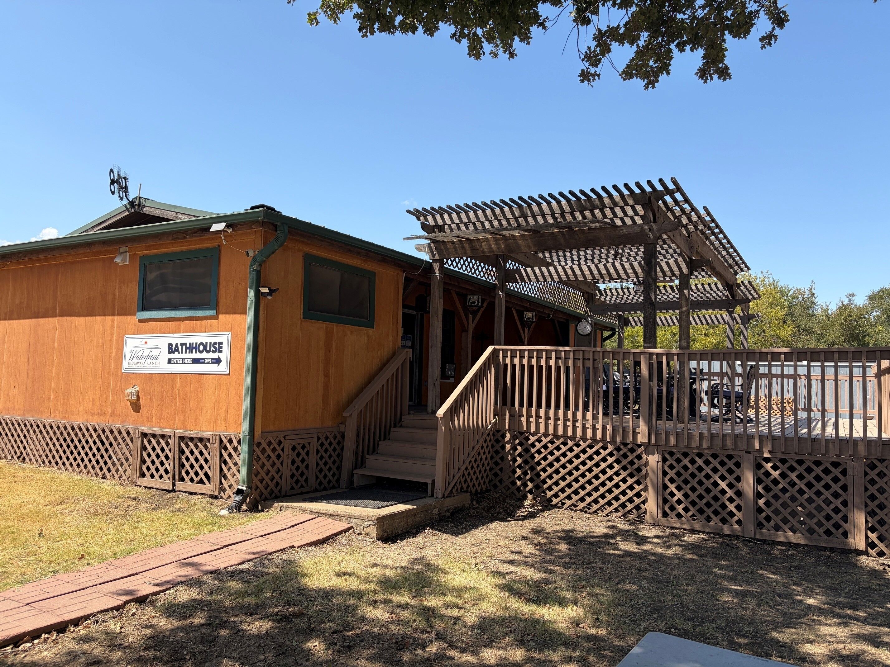 Un bâtiment en bois abritant des bains, avec une enseigne, une véranda et une clôture en bois.
