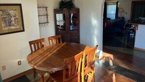 A dining room with a wooden table and chairs, a cabinet with glassware, and a framed picture on the wall. - Lakefront Retreat on 14+ Acres | Unforgettable Lake Getaway (Little Elm)