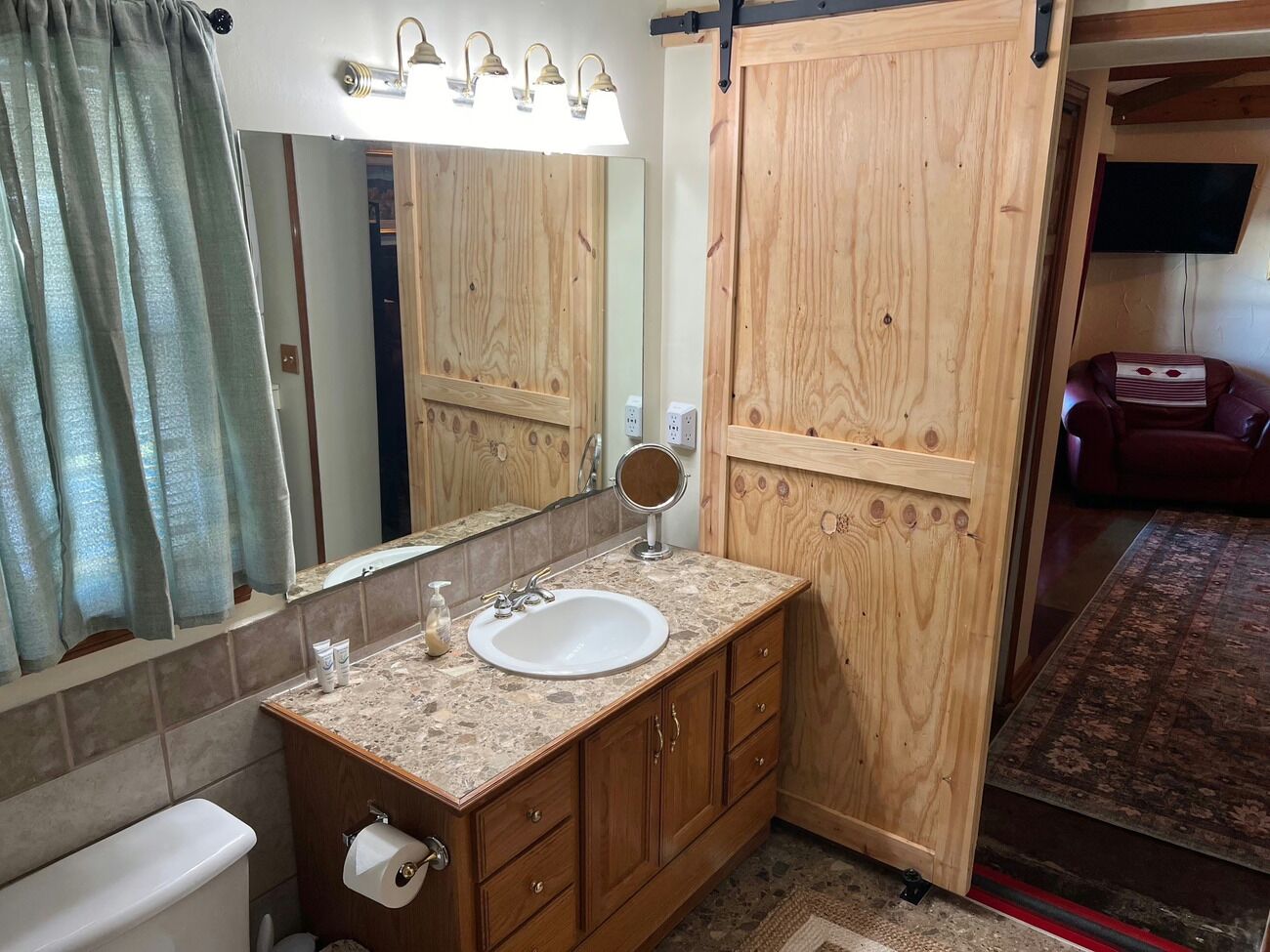 Une salle de bain avec un meuble-lavabo en bois, un évier, un miroir et un espace douche.