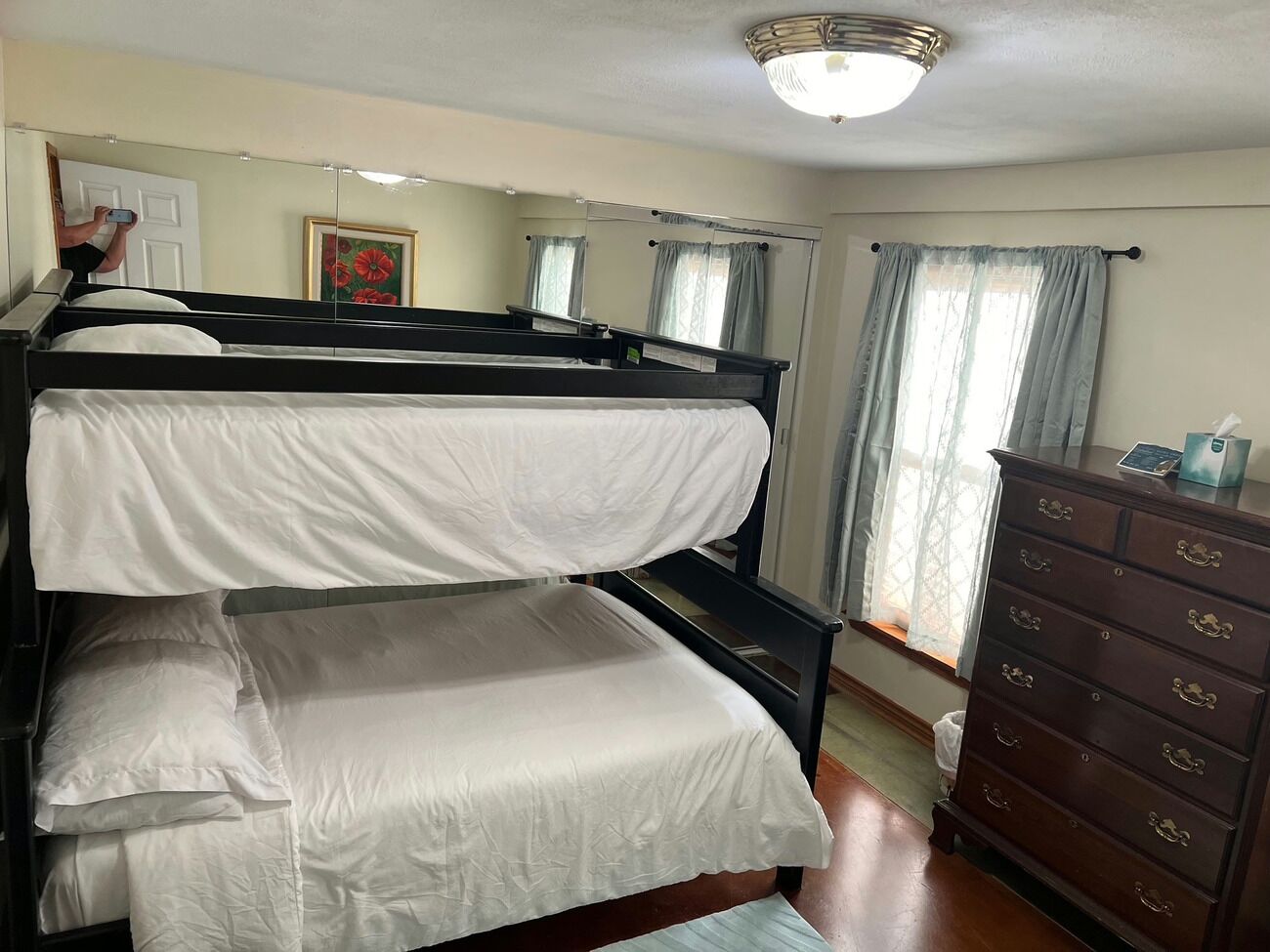 A bunk bed room with a dresser and a mirror.