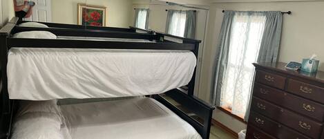 A bunk bed room with a dresser and a mirror.