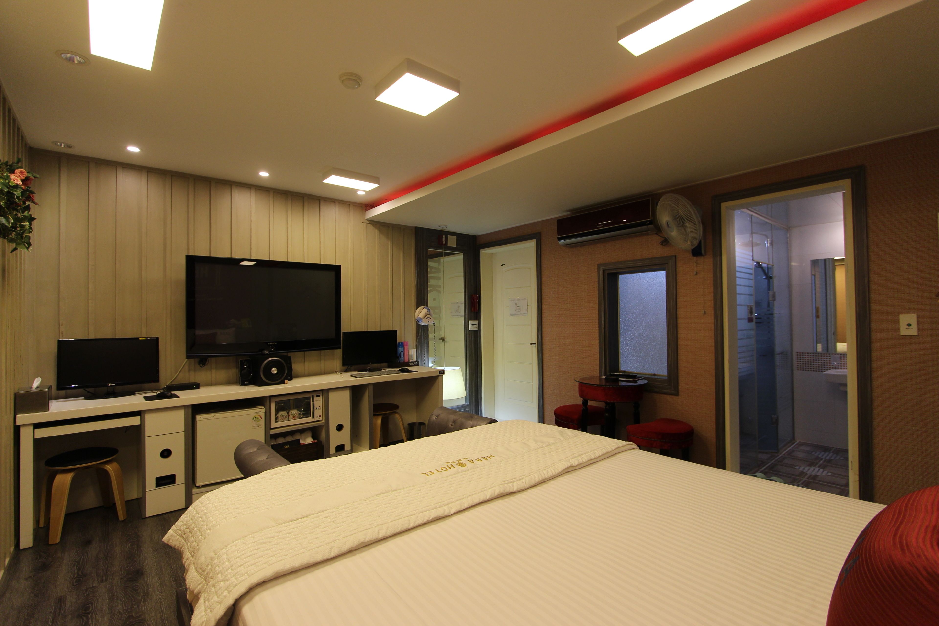 A hotel room with a bed, desk, television, and a small kitchenette.