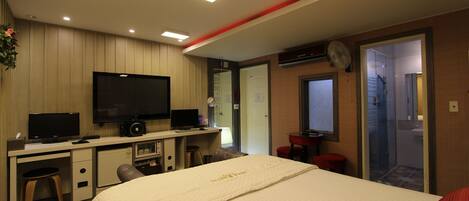 A hotel room with a bed, desk, television, and a small kitchenette.