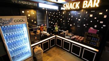A snack bar with a refrigerator stocked with bottled water, a coffee machine, and various snacks.