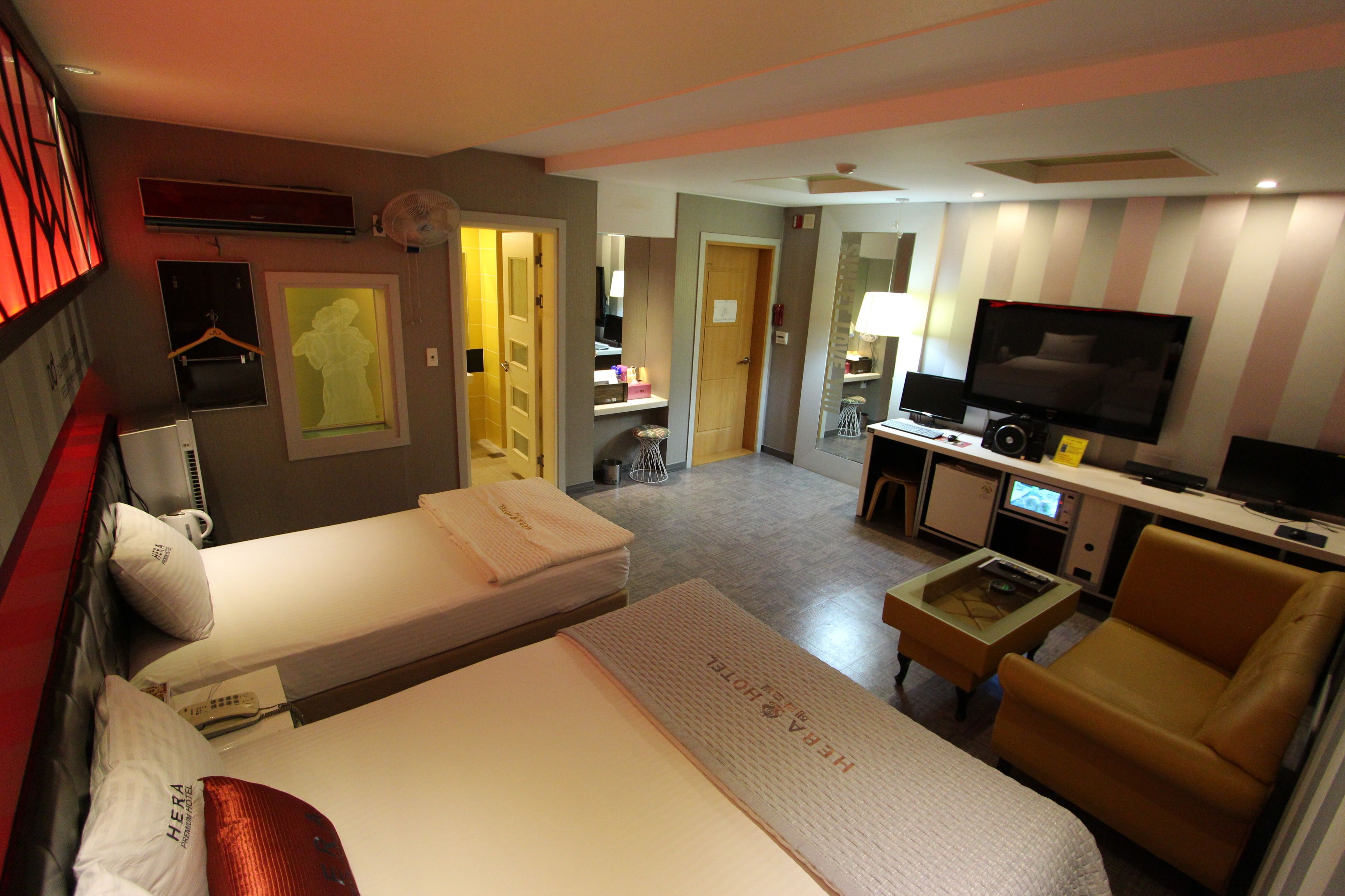 A hotel room with two beds, a TV, a desk, and a chair.
