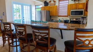 Una cocina con armarios de madera, un refrigerador de acero inoxidable, un microondas y una encimera de granito.