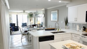 A modern kitchen with white cabinetry, a dishwasher, and a dining area with a table and chairs.