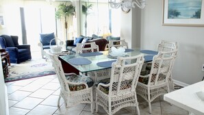 A dining area with a glass table, wicker chairs, and a view of the outdoors.