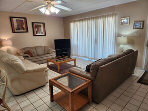 A living room with a sofa, armchair, coffee table, TV, and curtains.