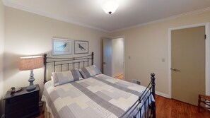 A bedroom with a bed, a nightstand, a lamp, and a door.