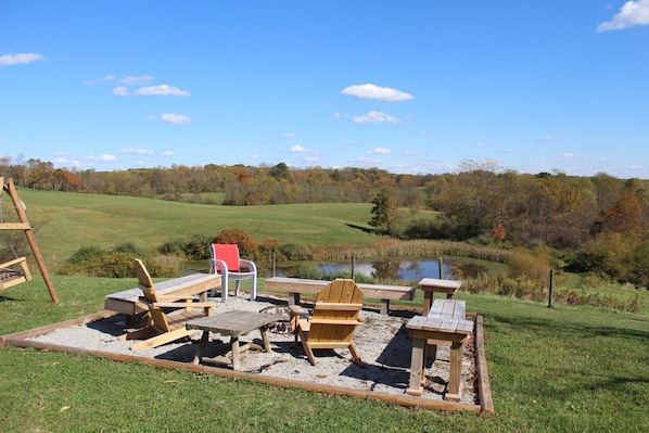 A wooden deck with picnic tables and chairs, a red chair, and a wooden swing set.