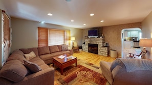 A living room with a sofa, coffee table, fireplace, and a television.