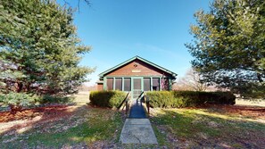 A wooden cabin with a pitched roof, surrounded by dense evergreen trees.