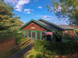 Una cabaña rústica con techo verde y terraza de madera.