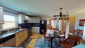 A kitchen with wooden cabinets, a dishwasher, a refrigerator, and a dining area with a table and chairs.