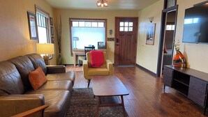 A living room with a leather sofa, a wooden coffee table, a yellow armchair, and a TV stand. - Historic Downtown Location │Heart of Bend │Walk Everywhere │Hot Tub │High Demand (Bend)