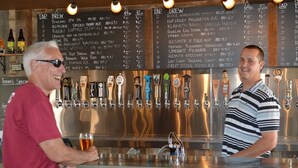 A bar with a tap list and a bartender. - Historic Downtown Location │Heart of Bend │Walk Everywhere │Hot Tub │High Demand (Bend)