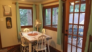 A dining area with a table and chairs, a fan, and a view of the outside. - Immaculate Seashell River Cabin at Estes Park (Estes Park)