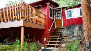 A red cabin with a wooden balcony, a wooden staircase, and a stone wall. - Immaculate Seashell River Cabin at Estes Park (Estes Park)