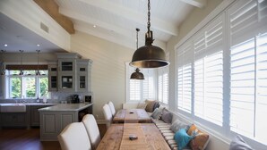 A spacious kitchen with a dining area, large windows, and a hanging light fixture. - Playa Penthouse (Ocean Views) (Carpinteria)
