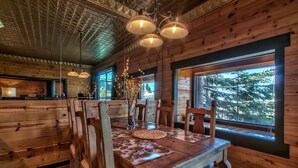 Un intérieur en bois avec une table à manger, des chaises et des luminaires suspendus.