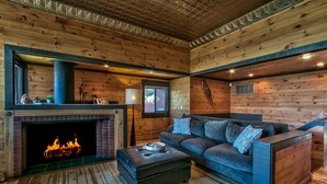 L’intérieur d’un chalet chaleureux, avec une cheminée, un canapé et un plancher en bois.