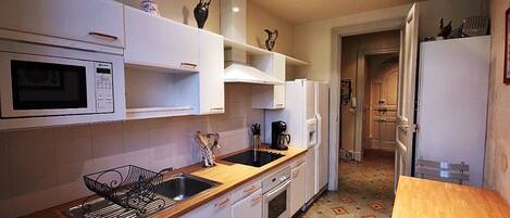 A compact kitchen with white cabinets, a microwave, a sink, and a coffee maker.