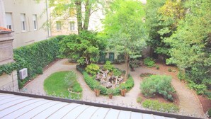 Ein Innenhof mit einem zentralen Steinelement, umgeben von verschiedenen Pflanzen und Bäumen.