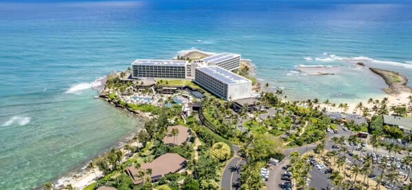 A coastal hotel with a pool, beachfront view, and multiple buildings.