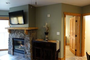 A living room with a stone fireplace, a mounted television, and a wooden door.
