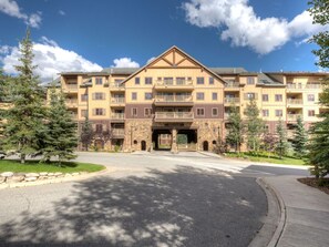 A multi-story hotel with a central entrance, balconies, and a stone facade.