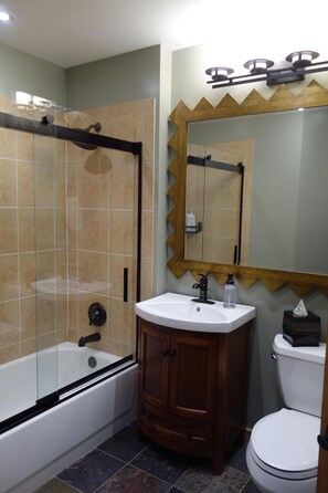 Een badkamer met een bad, wastafel, spiegel en toilet.